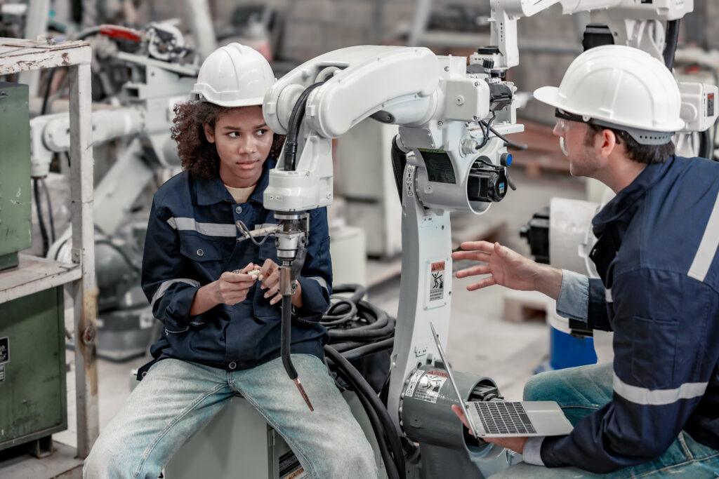 The experienced robotics technician supervisor mentors the female trainee in automating processes, configuring machinery, and ensuring reliable operation, emphasising technical skill development.